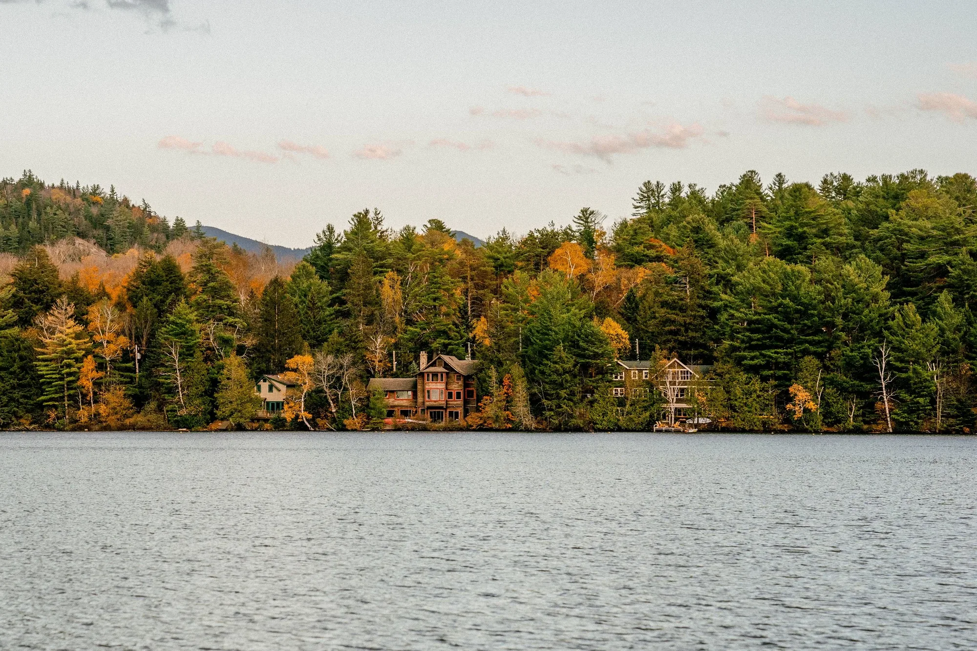 A residential home on a wooded lakeshore at dusk, representing the kind of homes Coastal Vacation Properties manages