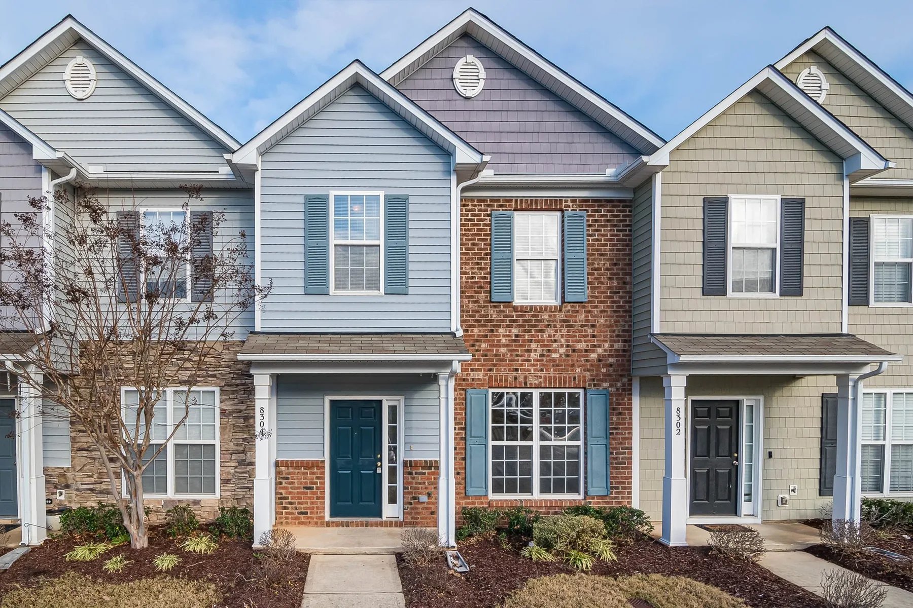 A row of two-story residential townhomes with brick and siding facades